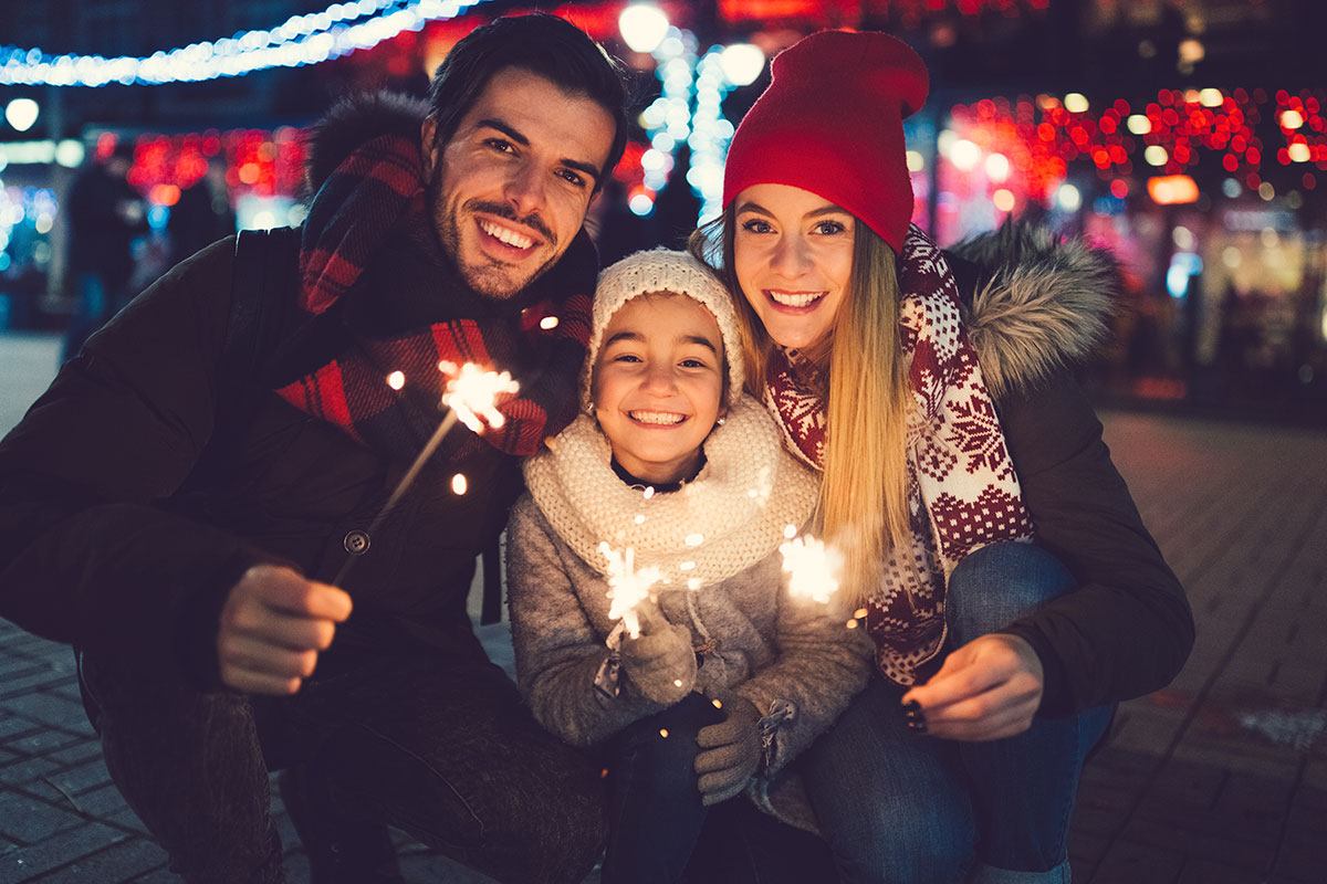 A family posing for a photo outside at night holding sparklers | Motif