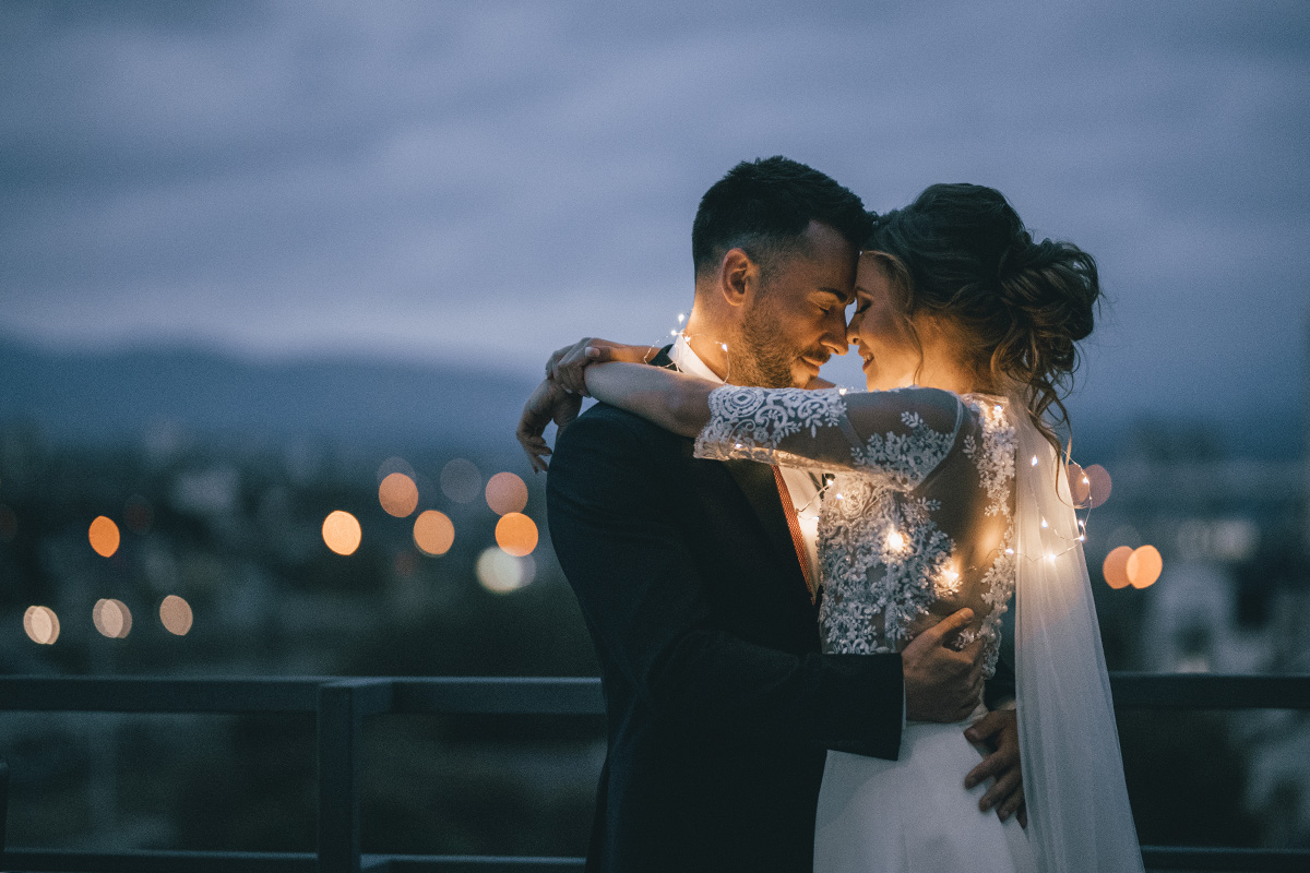 A bride and groom hugging outside with lights on the brides dress | Motif