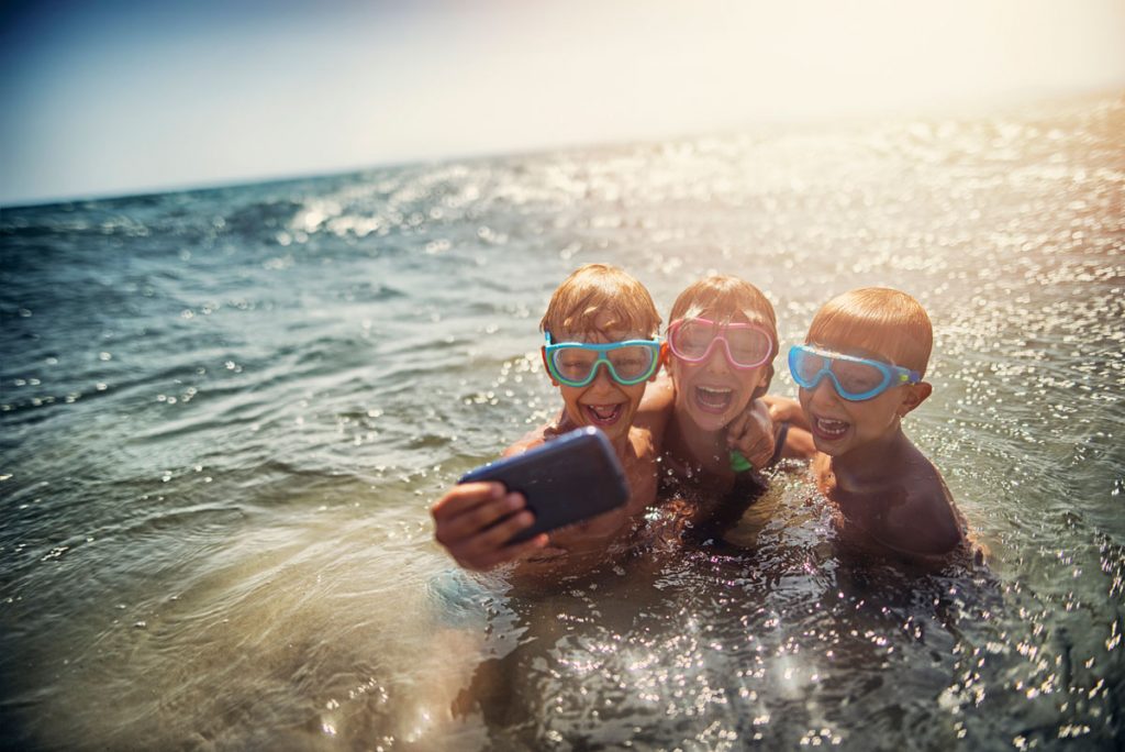 A group of kids taking a selfie in the ocean | Motif