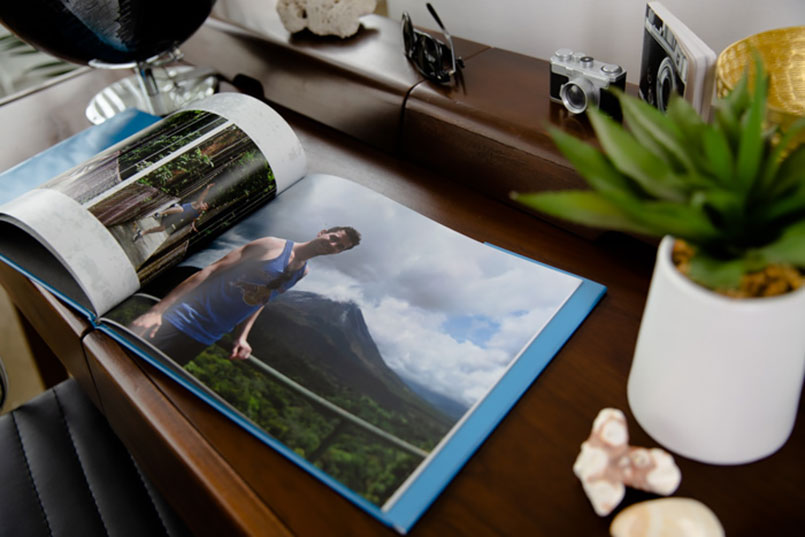 A custom photo book on a wood table with a picture of a man standing in front of a mountain | Motif