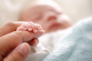 A newborn baby holding their mother’s finger | Motif