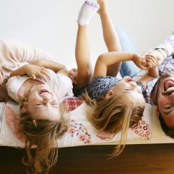 A family taking a group photo hanging upside down on a bed | Motif