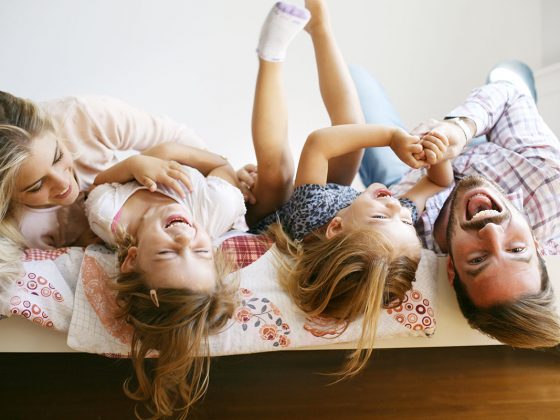 A family taking a group photo hanging upside down on a bed | Motif