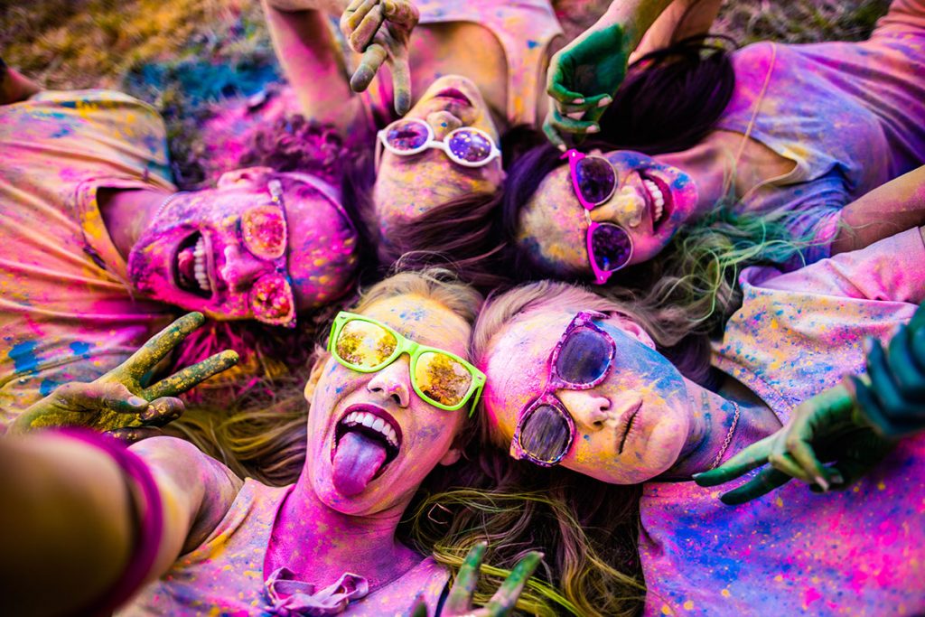 A group of girls taking a selfie after being covered in colored powder | Motif
