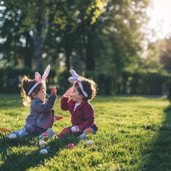 Two very young kids high-fiving during an Easter egg hunt | Motif