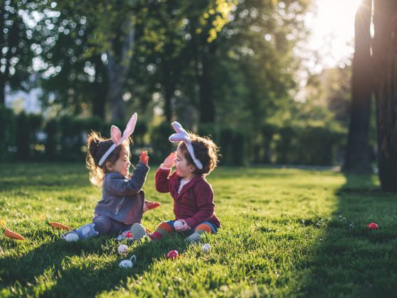 Two very young kids high-fiving during an Easter egg hunt | Motif