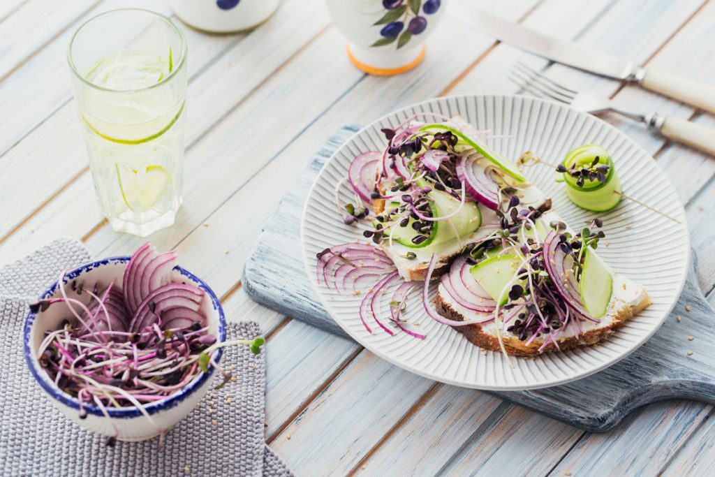 A plate of veggies on toast with a bowl of red onions | Motif