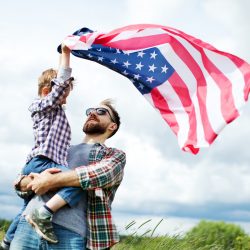 A father holding his son who is holding an American Flag | Motif