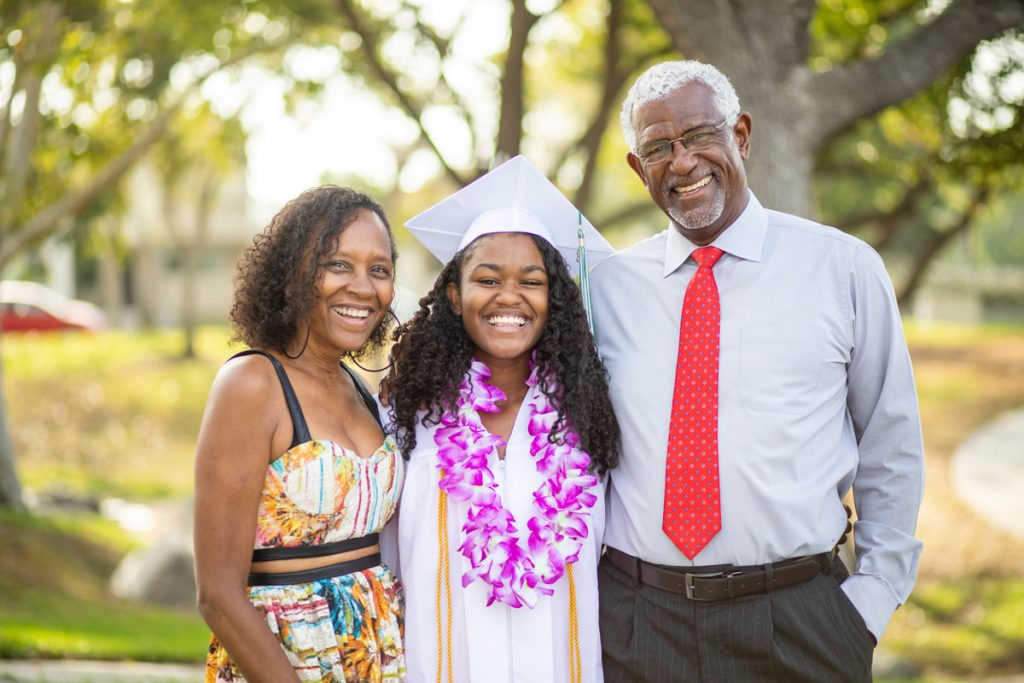 A college graduate taking a picture with her parents | Motif