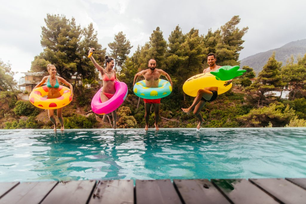 Friends with inflatable rings jumping in the swimming pool