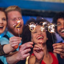 Joyful young people holding sparklers in a club