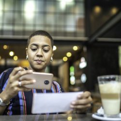 Young woman depositing check by phone in the cafe