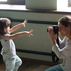 Mom photographer making photo of kid daughter on digital camera
