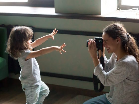 Mom photographer making photo of kid daughter on digital camera