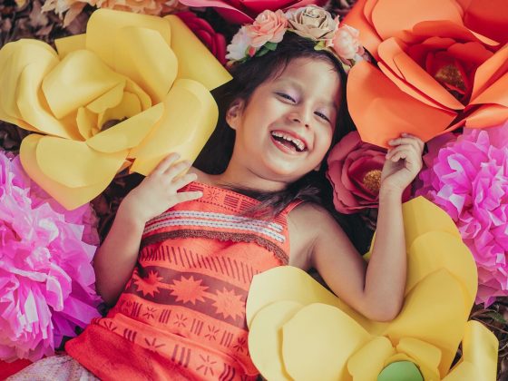 A little girl with oversized craft flowers.
