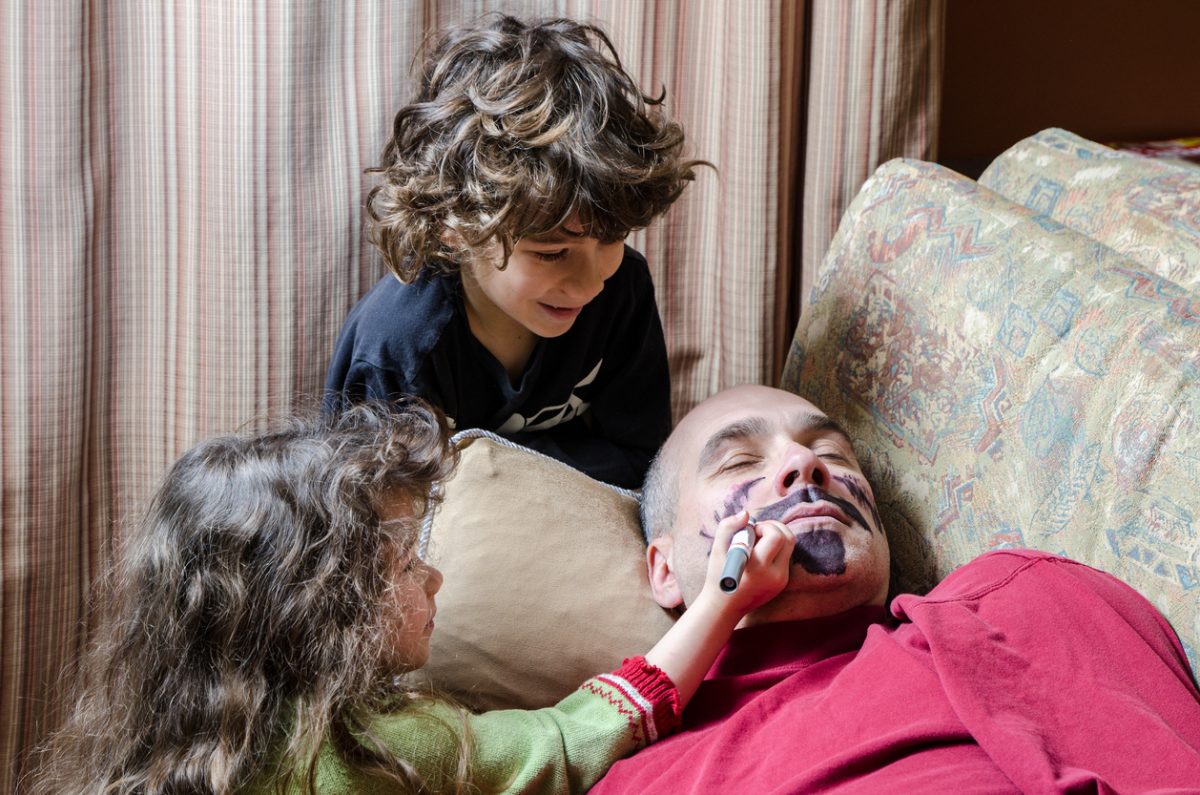 Kids drawing a mustache on father's face April fools day