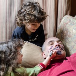 Kids drawing a mustache on father's face April fools day