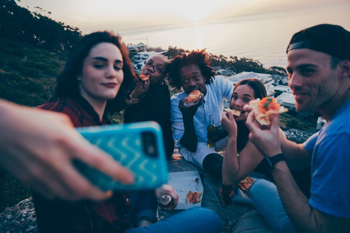 A group of friends taking a selfie while having a picnic.