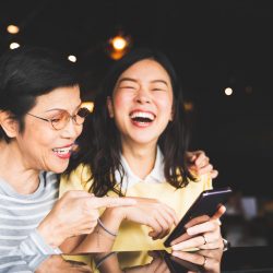 Asian mother and daughter laugh at memories in their Apple Photos organization.