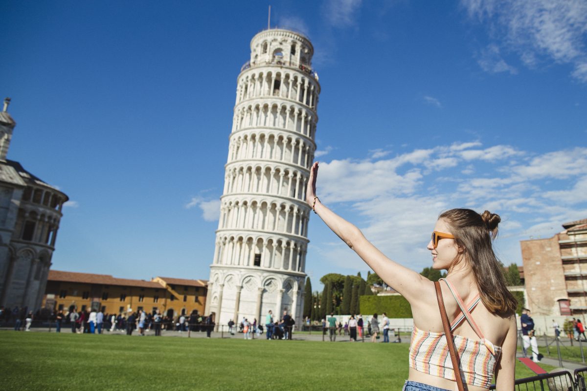 Young woman holding up Leaning Tower of Pisa is classic forced perspective photography.