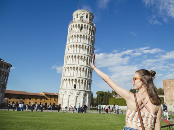 Young woman holding up Leaning Tower of Pisa is classic forced perspective photography.