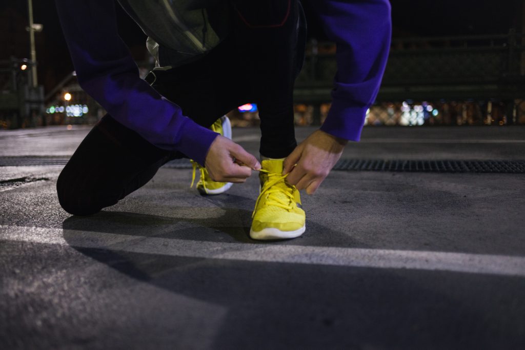 Runner in blue jacket ties yellow shoes, creating contrasting color photography.