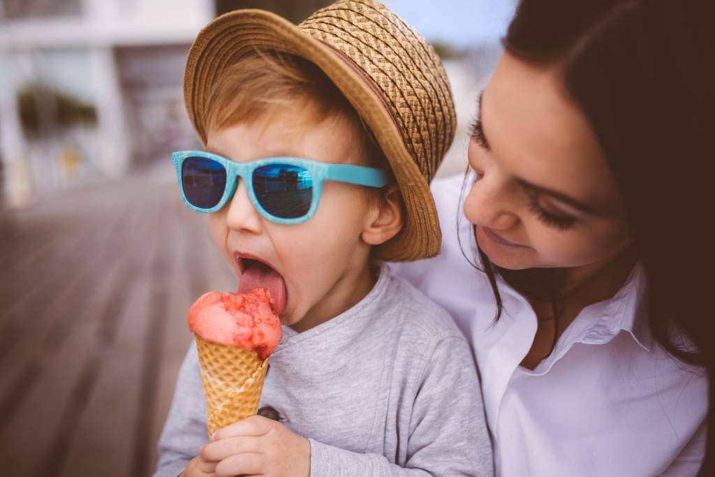 Mom gives son ice cream cone to coax him into the summer family picture.