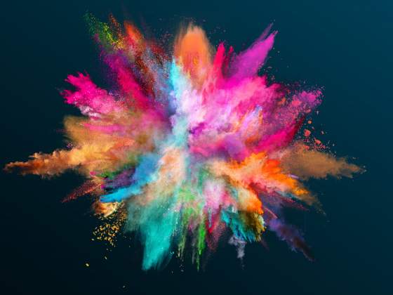 Various color powder explodes on black background to inspire better photo book design.