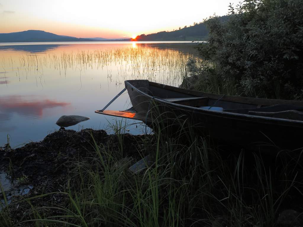 Using night photography tips, capture a midsummer sunset on the lake with row boat.