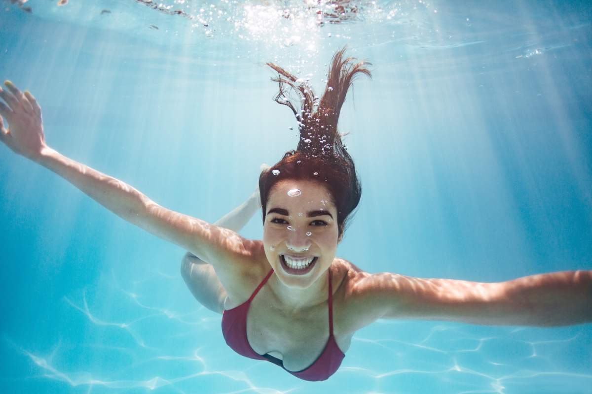 Young woman in red bikini smiles at camera during an underwater photography shoot.