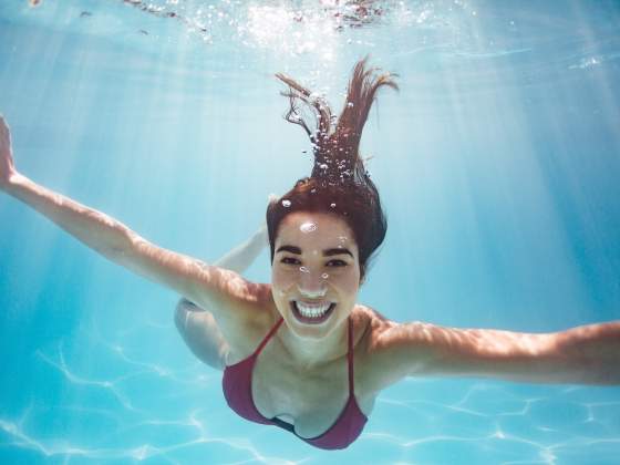 Young woman in red bikini smiles at camera during an underwater photography shoot.