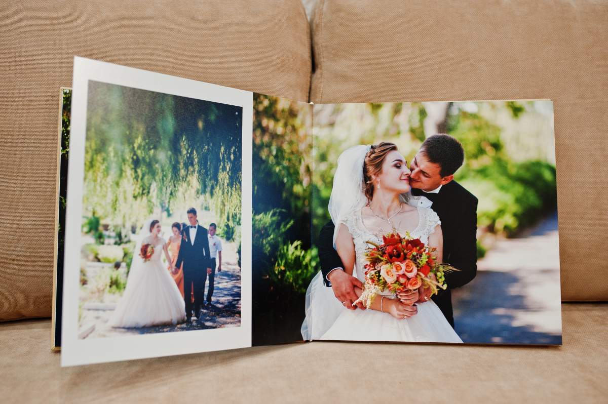 An open wedding album on a sofa shows happy newlyweds know how to create Apple photo book memories.