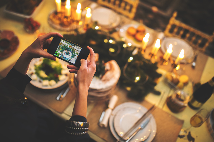 Woman holds iPhone over fully dressed table to capture sweet Thanksgiving pictures.