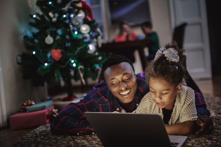 Dad and daughter lie on the floor, use a Macbook to create DIY Christmas cards with Motif.