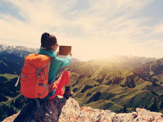 woman backpacker use digital tablet taking photo on mountain peak
