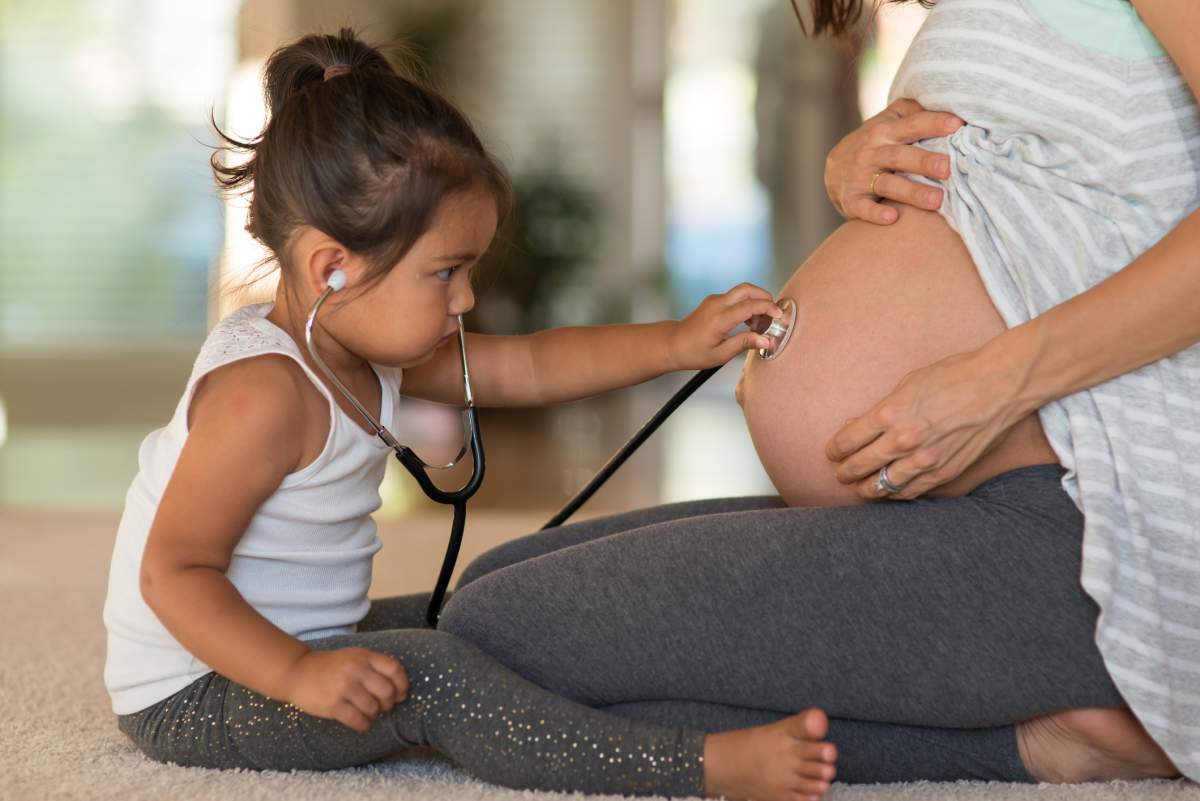 Cute toddler listening to her pregnant mother's belly