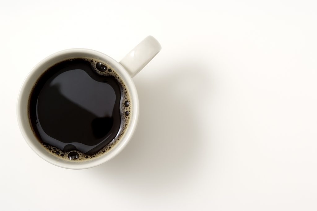 Overhead shot of a cup of coffee isolated on white background with soft shadow.