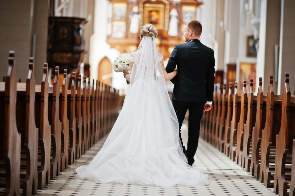 Photosession of stylish wedding couple on catholic church