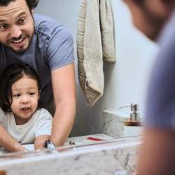 Young dad and cute son washing hands in the bathroom