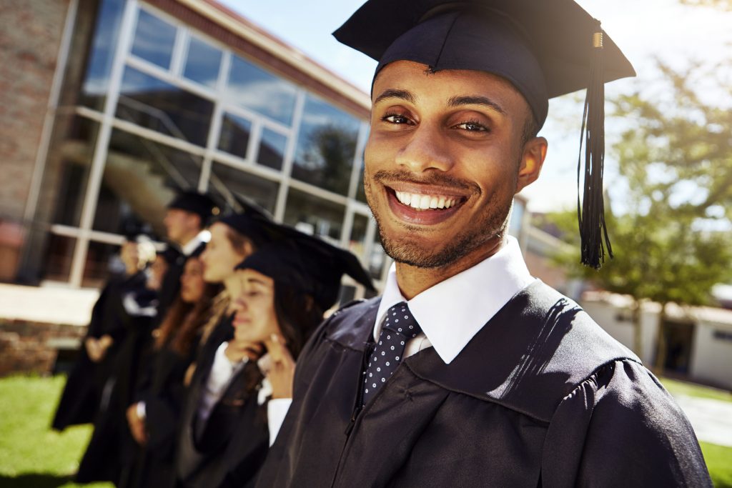 Portrait of a smiling university student on graduation day with classmates in the background