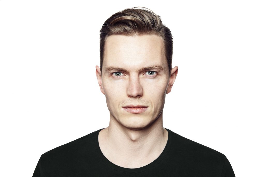 Studio shot of young man looking at the camera. Isolated on white background. Horizontal format, he has a serious face, he is wearing a black T-shirt.