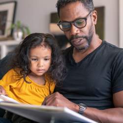 Affectionate father reading book with adorable daughter