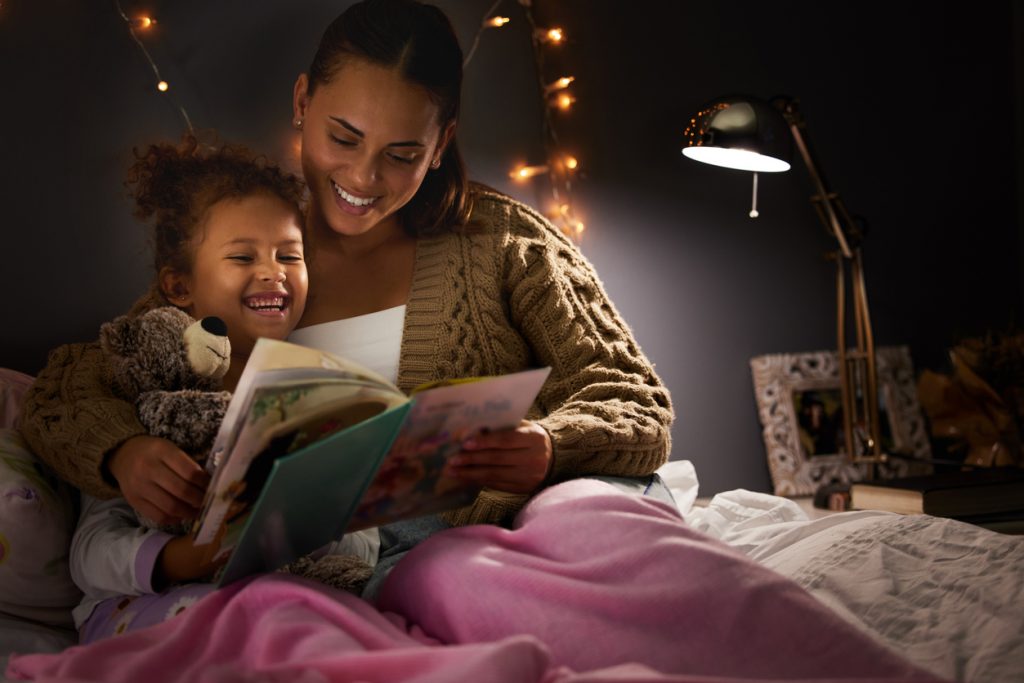 young mother reading her daughter a bedtime story